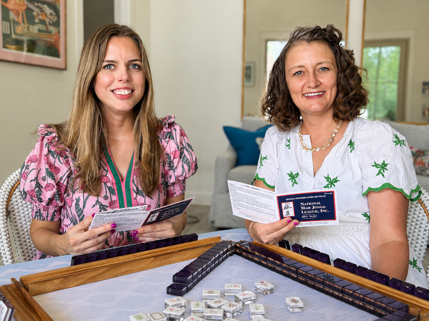 Megan and Martine holding National Mah Jongg League cards at a mahjong table